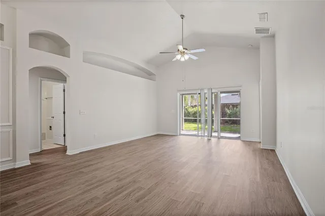 an empty room with wooden floor chandelier and glass door