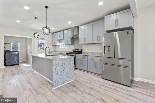 a kitchen with stainless steel appliances granite countertop a refrigerator a sink dishwasher a stove and white cabinets with wooden floor