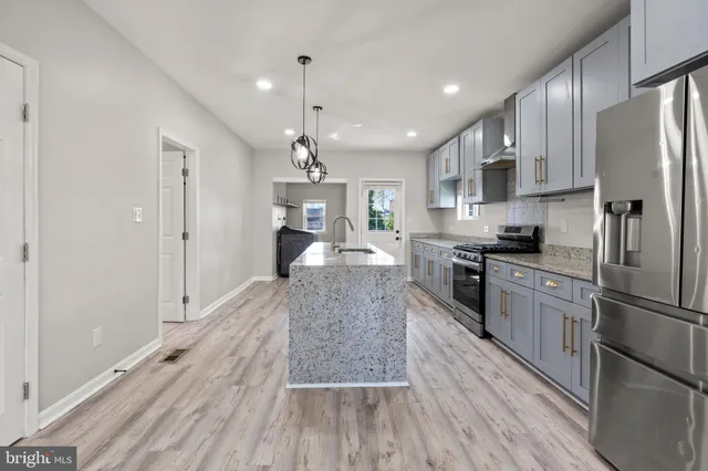 a large kitchen with cabinets wooden floor stainless steel appliances and a window