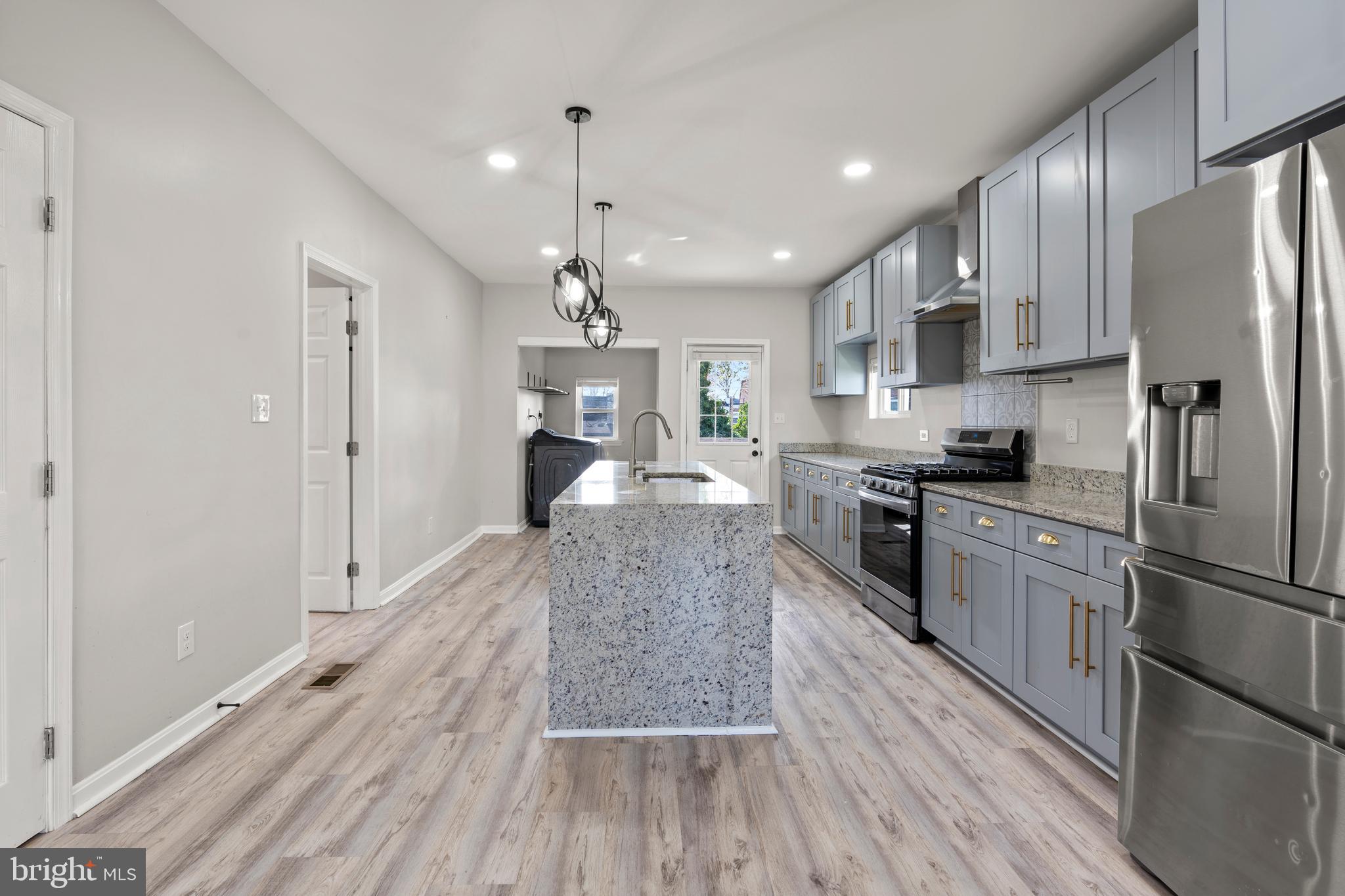 3809 West Cold Spring Lane Baltimore, MD 21215 - Photo 14 of 47 a large kitchen with cabinets wooden floor stainless steel appliances and a window