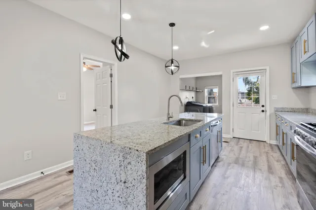 a kitchen with granite countertop a sink stove and refrigerator