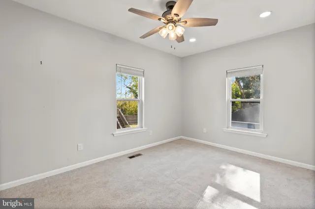 an empty room with windows and fan
