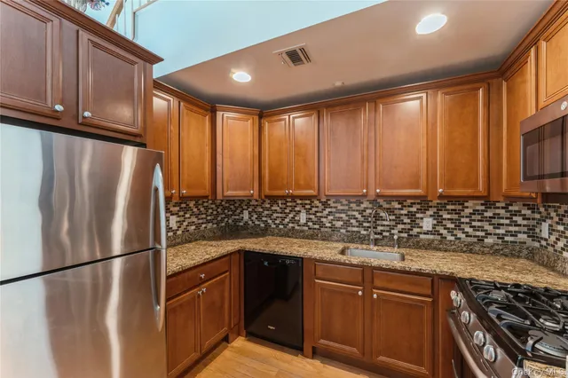 a kitchen with granite countertop a refrigerator stove and cabinets