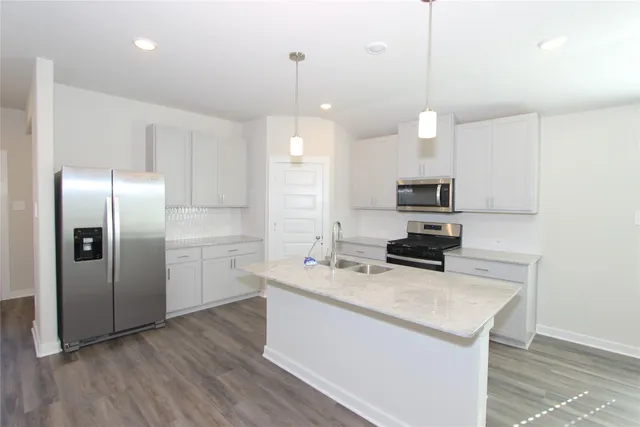 a kitchen with stainless steel appliances granite countertop a sink a stove a refrigerator and island with wooden floor