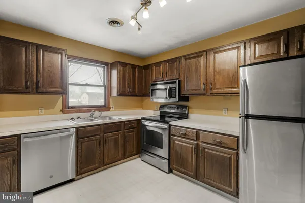 a kitchen with stainless steel appliances granite countertop a refrigerator a sink dishwasher a stove top oven a refrigerator with island and cabinets