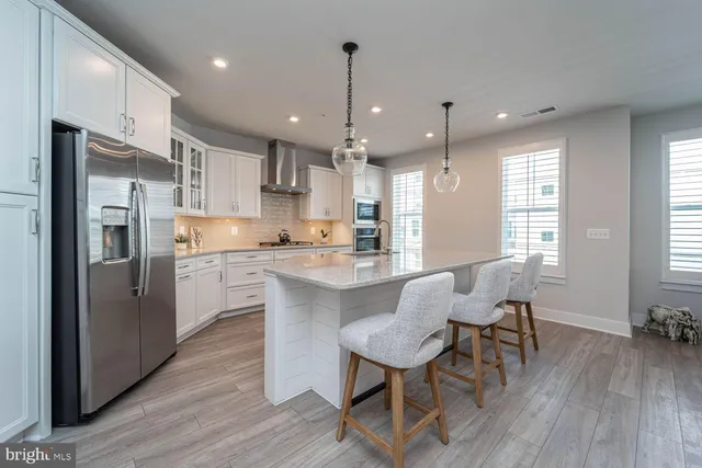 a kitchen with stainless steel appliances granite countertop a refrigerator a stove a sink dishwasher a dining table and chairs with wooden floor