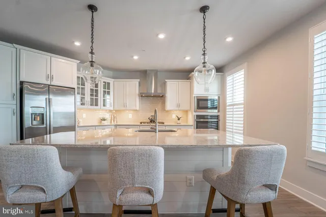 a kitchen with kitchen island a dining table chairs stainless steel appliances and cabinets