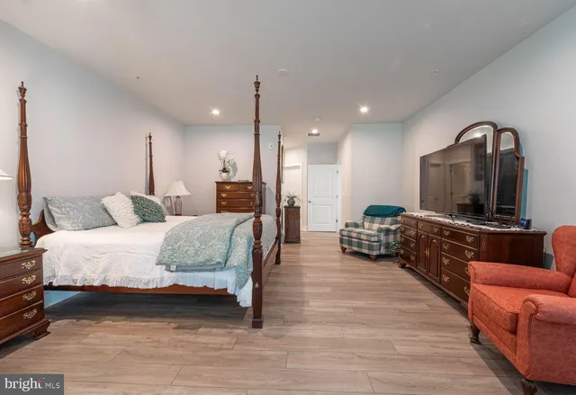 a spacious bedroom with a bed a couch and a dresser with wooden floor