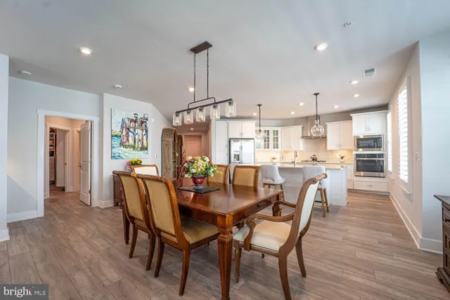 a view of a dining room and livingroom with furniture wooden floor kitchen view and a window