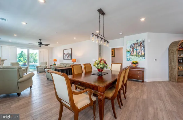a view of a dining room and livingroom with furniture wooden floor a rug a rug a painting and a chandelier