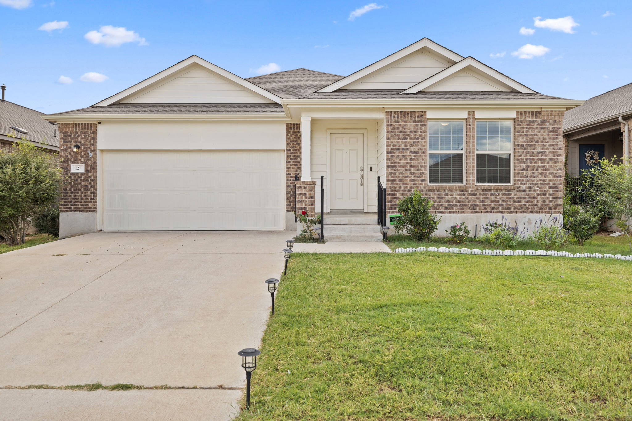 Ranch-style house with brick siding, a shingled roof, concrete driveway, a front lawn, and an attached garage