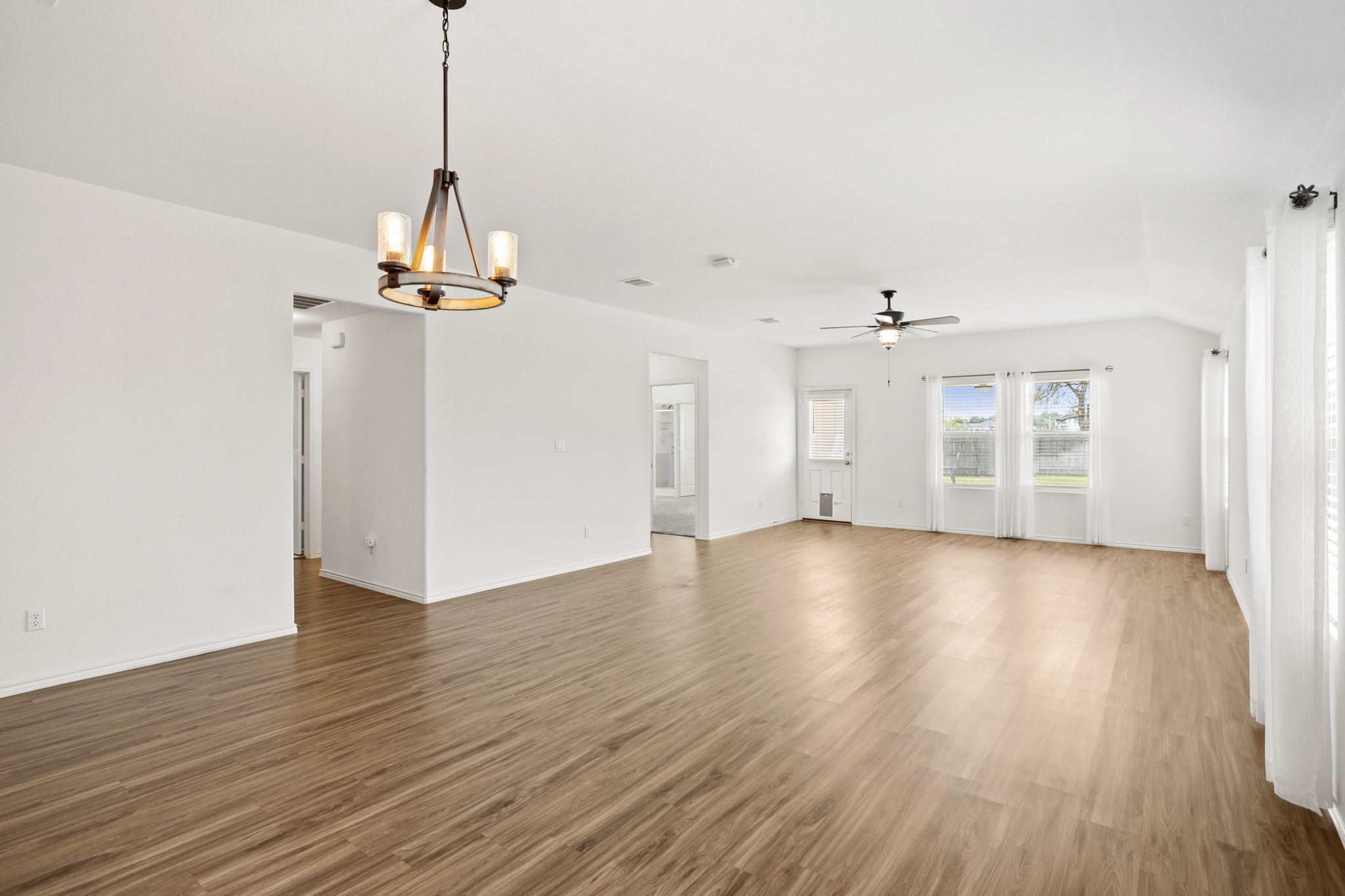 127 George Kimble Cove Bastrop, TX 78602 - Photo 16 of 40 Unfurnished living room featuring wood finished floors, a chandelier, and a ceiling fan