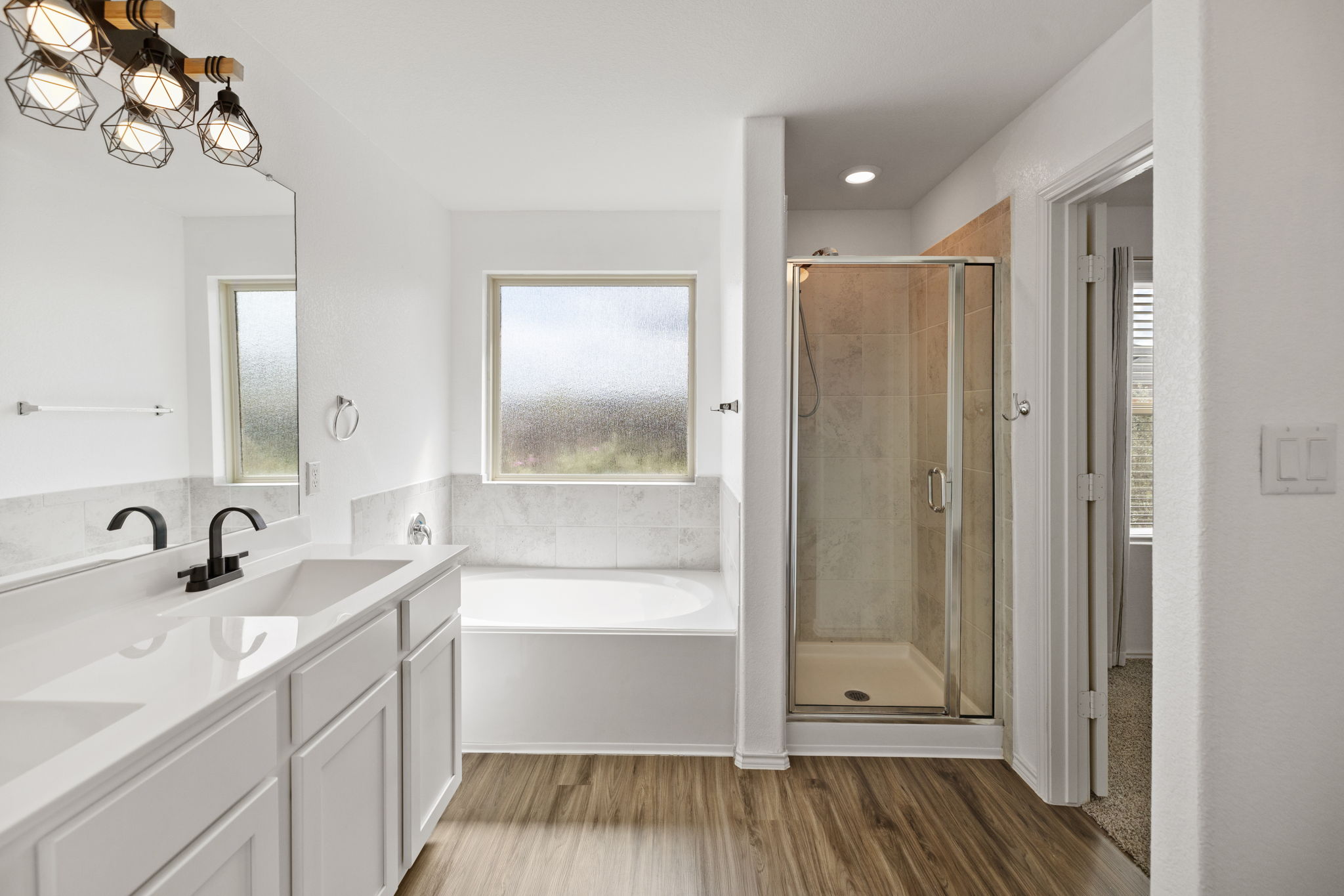 127 George Kimble Cove Bastrop, TX 78602 - Photo 32 of 40 Full bathroom featuring a bath, light wood-style floors, a shower stall, and double vanity