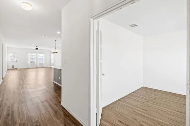 an empty room with wooden floor and windows