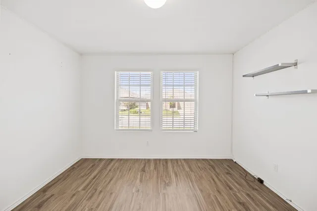 a kitchen with stainless steel appliances a stove a sink a refrigerator and white cabinets with wooden floor