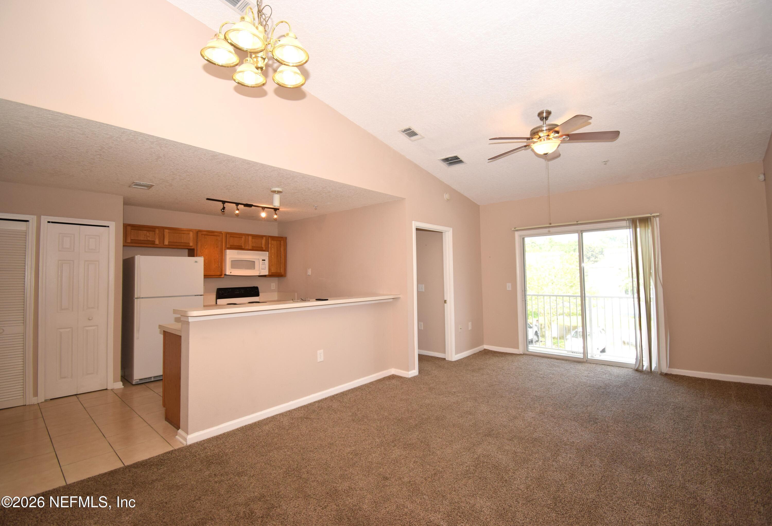7920 Merrill Road, Unit 1811 Jacksonville, FL 32277 - Photo 3 of 15 a view of a kitchen with furniture a ceiling fan and a window