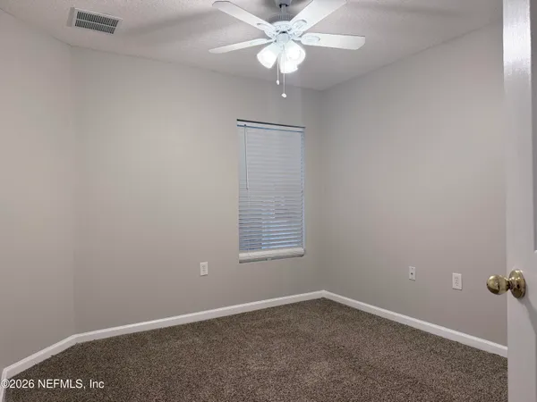 an empty room with a window and a fan