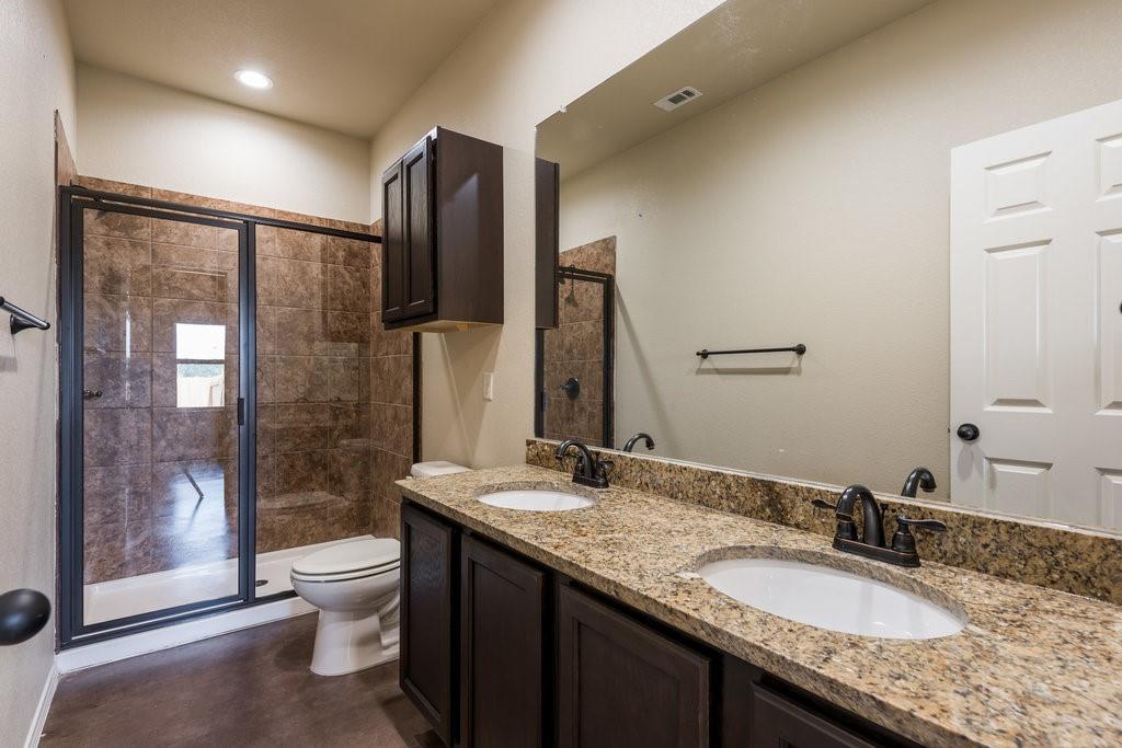 491 Jack Rabbit Lane, Unit A Buda, TX 78610 - Photo 12 of 22 Double vanity with stone counters and a tiled shower create a functional bathroom.
