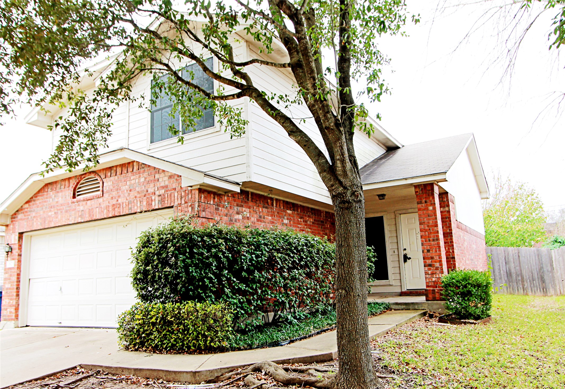 View of front of house with an attached garage, brick siding, and driveway