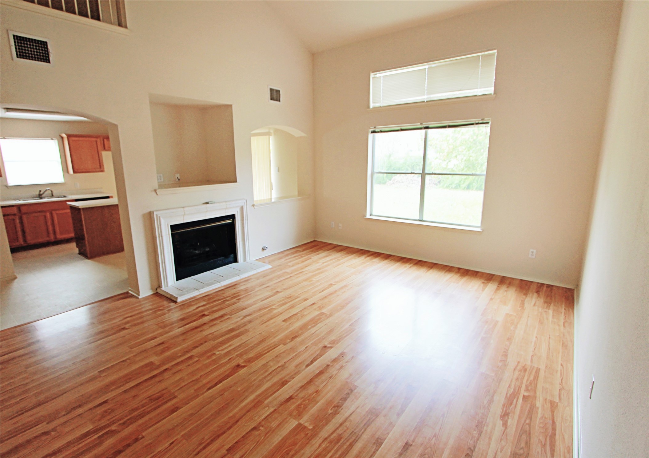 1821 Friars Tale Lane Austin, TX 78748 - Photo 2 of 20 Unfurnished living room with a fireplace with raised hearth, light wood-style flooring, arched walkways, and vaulted ceiling
