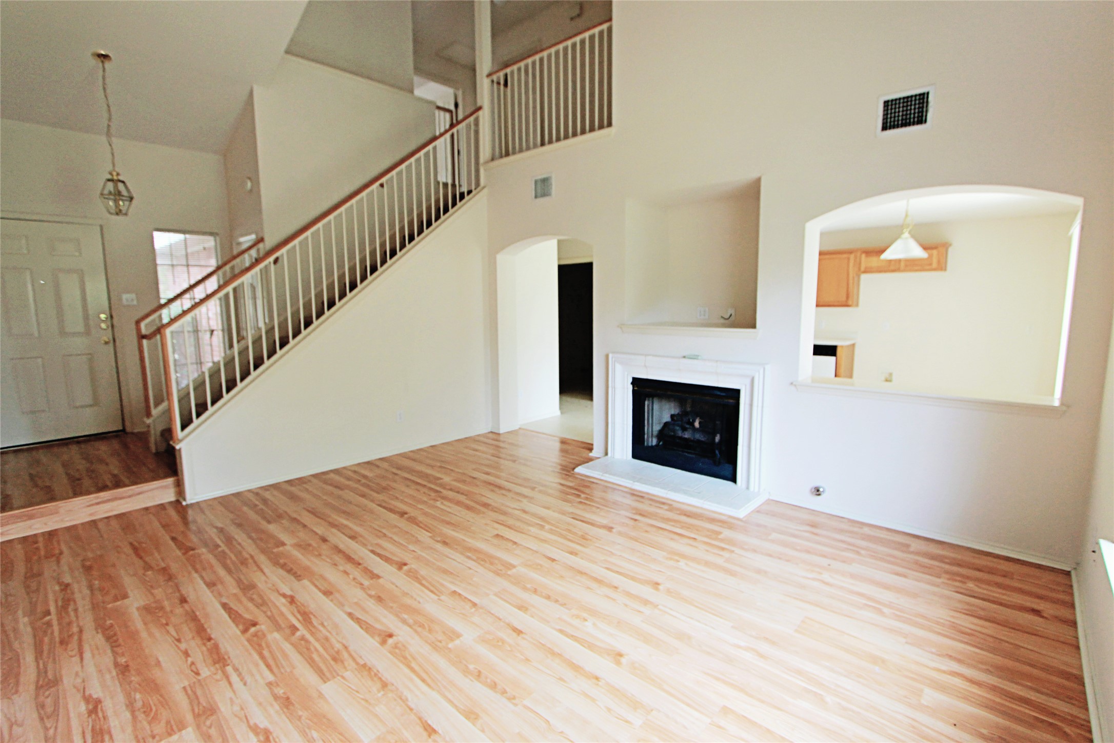 1821 Friars Tale Lane Austin, TX 78748 - Photo 4 of 20 Unfurnished living room featuring light wood-style floors, a fireplace with raised hearth, arched walkways, and lofted ceiling