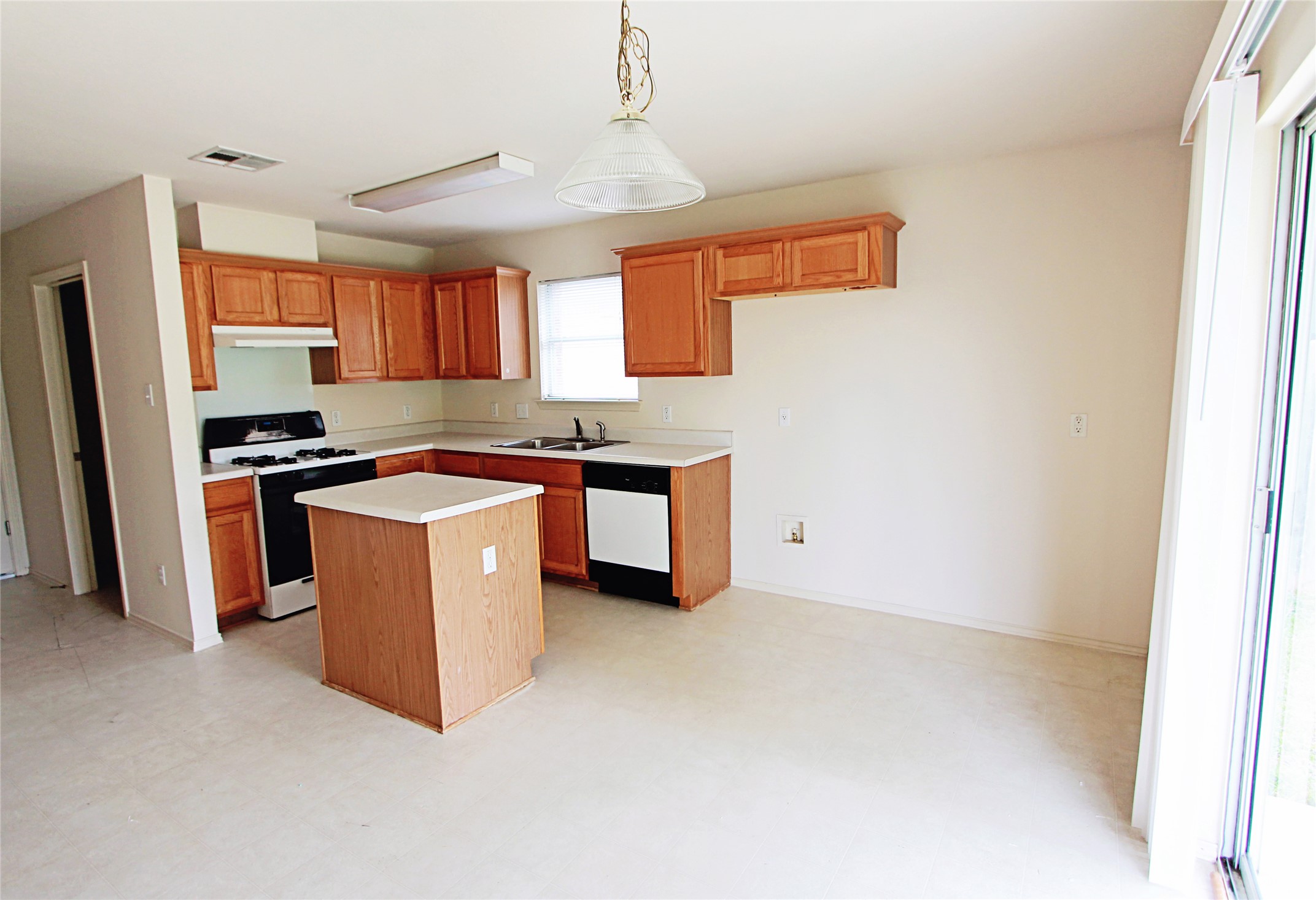 1821 Friars Tale Lane Austin, TX 78748 - Photo 8 of 20 Kitchen with light countertops, light floors, white gas range oven, wood finish cabinetry, and a center island