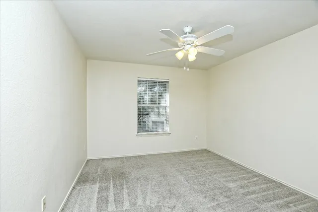 an empty room with a window and a fan