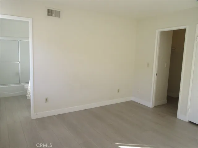 an empty room with fan and way to kitchen