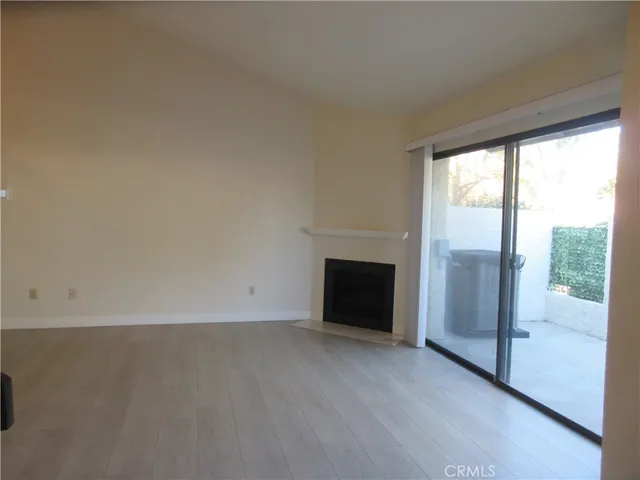 an empty room with wooden floor and a fireplace