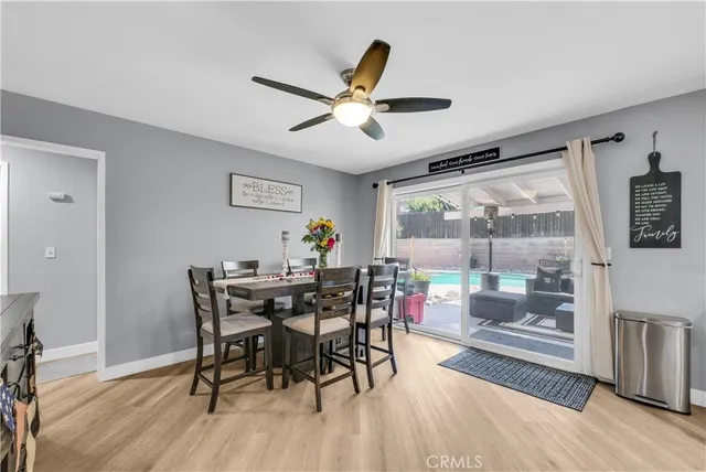 a dining room with wooden floor a chandelier fan a wooden table and chairs