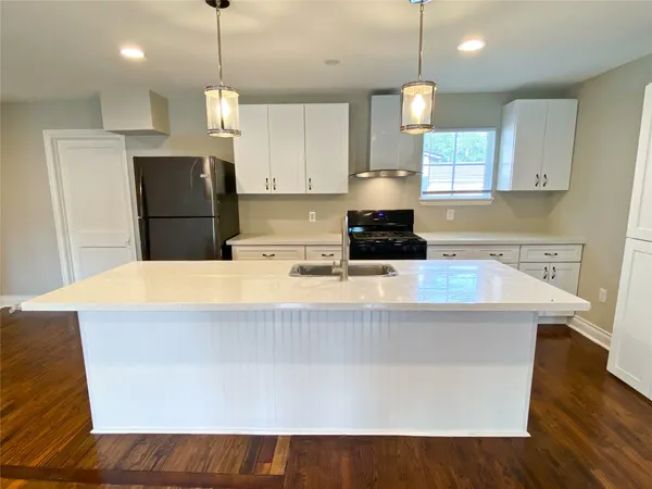 a kitchen with kitchen island a stove a refrigerator a sink and a wooden floor