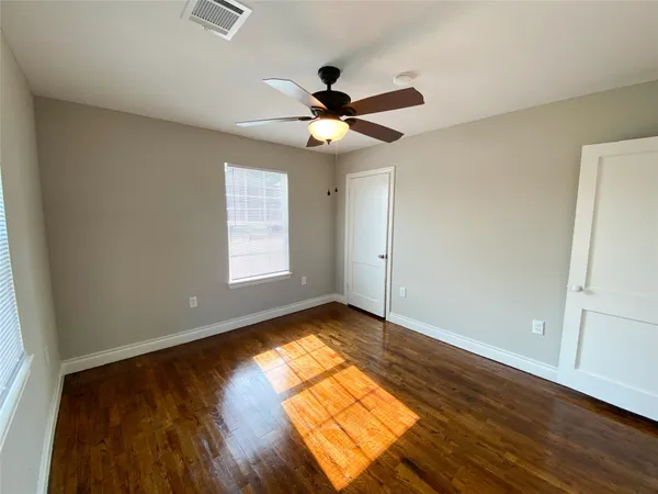 a view of empty room with wooden floor and fan