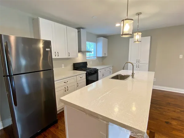 a kitchen with stainless steel appliances a refrigerator a sink a stove a microwave a dining table and chairs