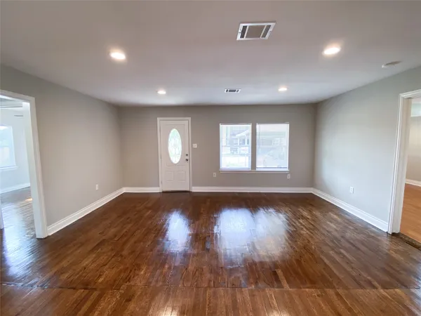 a view of an empty room with wooden floor and window