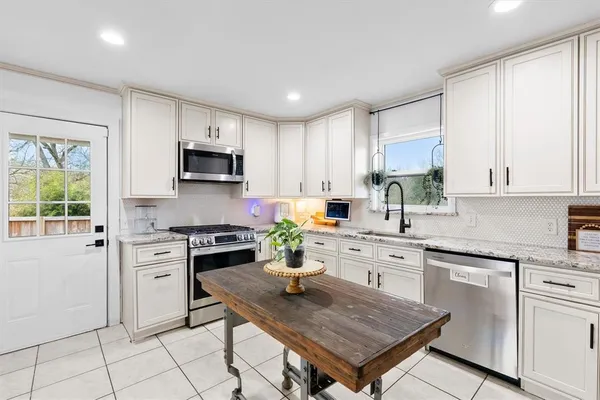 a kitchen with white cabinets a stove a sink dishwasher and a stove top oven with wooden floor