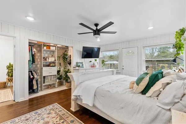 a bedroom with a large bed a flat tv screen and a dresser