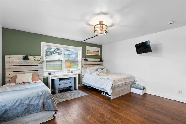 a bedroom with a bed and a flat tv screen on dresser