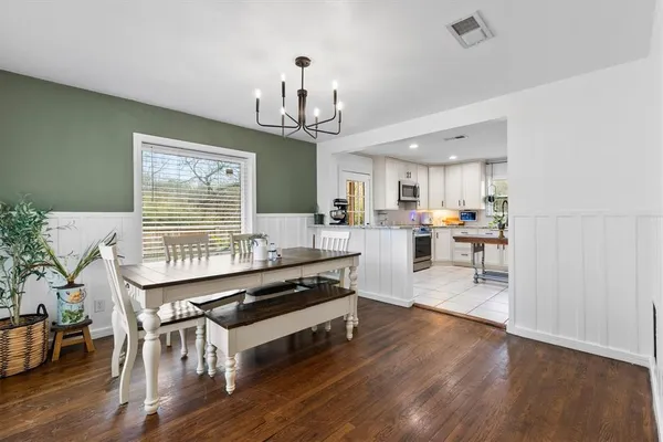 a kitchen with stainless steel appliances a dining table chairs stove and wooden floor
