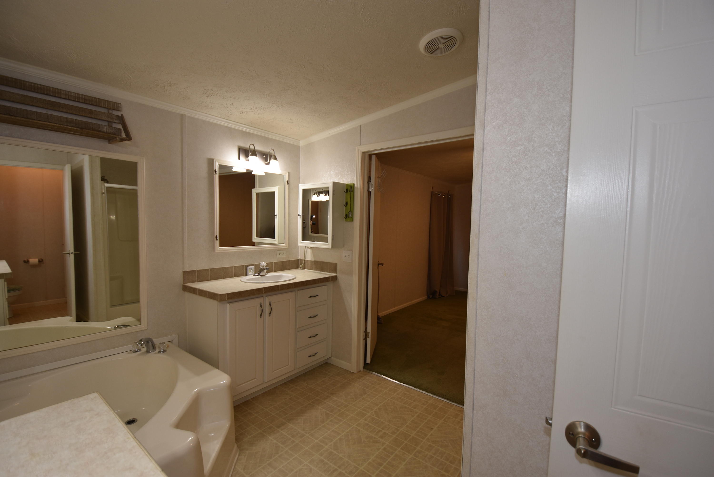 2953 Adams Road Crestview, FL 32536 - Photo 24 of 51 a bathroom with a granite countertop sink and mirror with bathtub