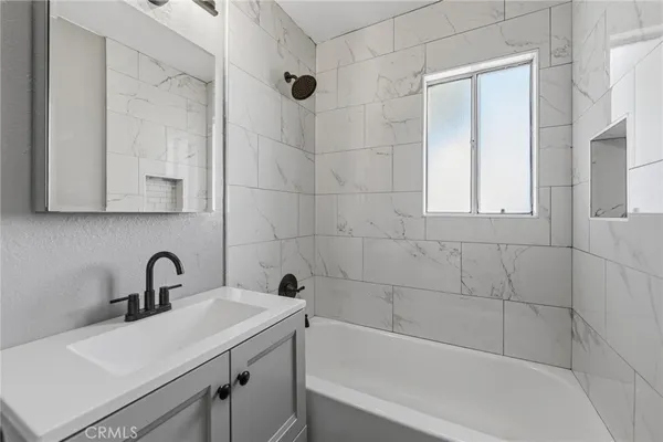 a bathroom with a sink and mirror with bathtub