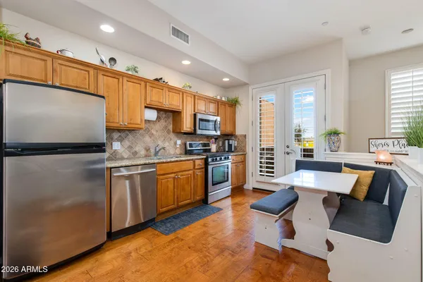 a large kitchen with stainless steel appliances granite countertop a refrigerator a stove a sink dishwasher and white cabinets with wooden floor