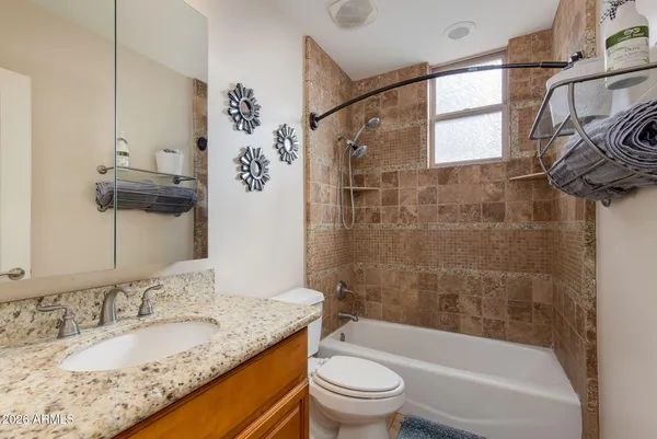 a bathroom with a granite countertop sink a toilet and bathtub