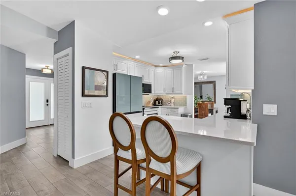 a kitchen with stainless steel appliances a dining table chairs a sink and cabinets
