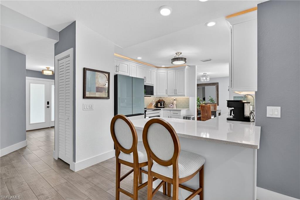 5270 Berkeley Drive Naples, FL 34112 - Photo 13 of 43 a kitchen with stainless steel appliances a dining table chairs a sink and cabinets