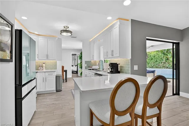 a kitchen with sink a refrigerator and chairs