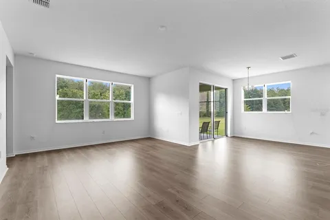 a view of an empty room with wooden floor and windows