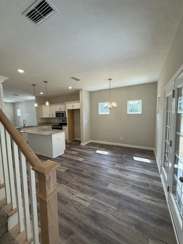 a view of kitchen and empty room with wooden floor