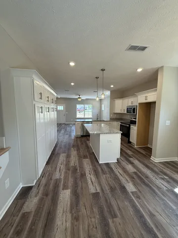 a view of kitchen with kitchen island wooden floor center island and stainless steel appliances