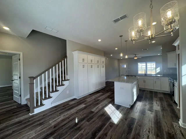 a open kitchen with white cabinets a sink a window and stainless steel appliances