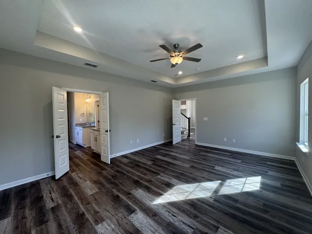 a view of an empty room and window a ceiling fan and wooden floor